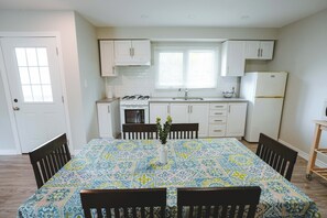 A compact kitchen with white cabinets, a stove, and a refrigerator. - Sandpiper Cottage - 3-Bedroom Cottage – Family Friendly (Trent Lakes)