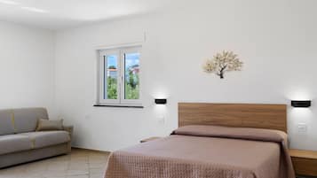 Ein Schlafzimmer mit einem Bett, einem Sofa, einem Fenster und einer Wandleuchte.