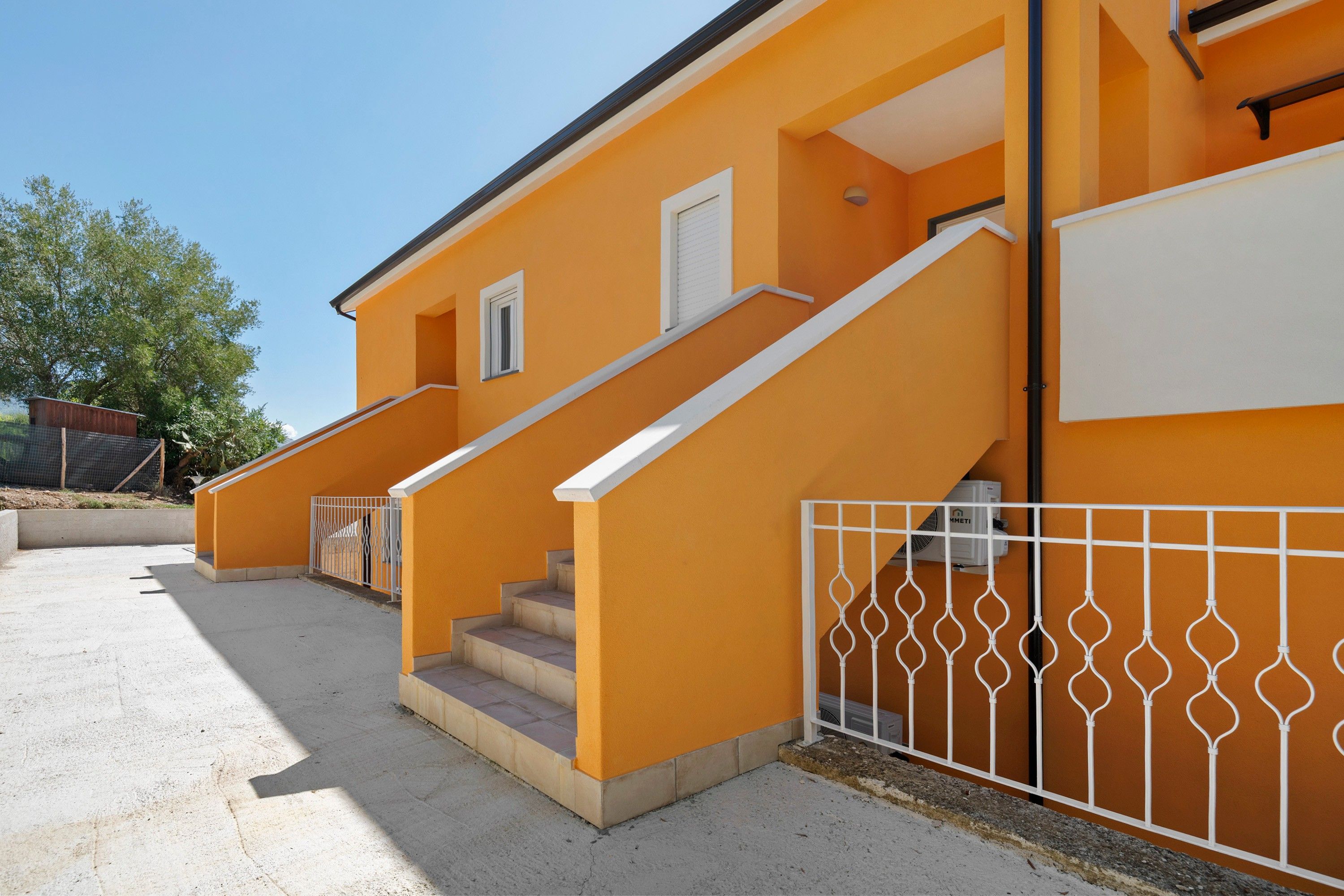 Un bâtiment à deux étages, doté d’un escalier et d’une clôture en métal blanc.