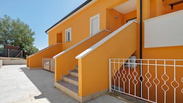 Un bâtiment à deux étages, doté d’un escalier et d’une clôture en métal blanc.