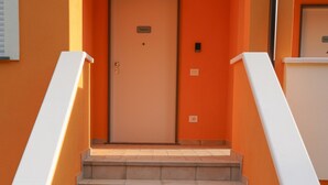 A staircase leading to a door with a sign above it, flanked by walls painted in a warm color. - Oliblu Holiday Home – Superior Taggiasca Apartment with Partial Sea View (Vibonati)