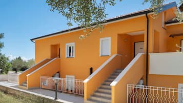 Un bâtiment à deux étages, avec un escalier menant à l’étage supérieur, un petit balcon et une balustrade blanche.