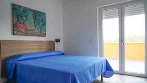 A bedroom with a bed, a painting on the wall, a window, and a door. - Oliblu Holiday Home – Superior Taggiasca Apartment with Partial Sea View (Vibonati)