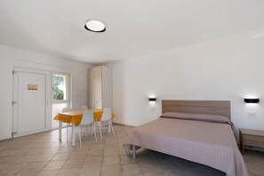 A bedroom with a bed, bedside tables, a window, and a dining area with chairs and a table. - Oliblu Holiday Home - Standard Frantoio Studio (Vibonati)
