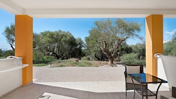 Un espace extérieur abrité, avec une table et des chaises, d’où l’on peut admirer les arbres et un chemin de gravier.