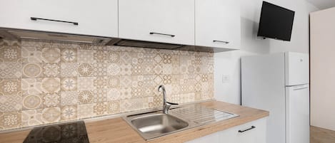 A modern kitchen with a patterned backsplash, stainless steel sink, wooden countertop, and a built-in oven.