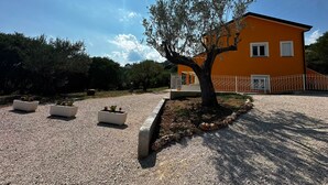 Ein Gebäude mit Baum davor, umgeben von Kies und Topfpflanzen.