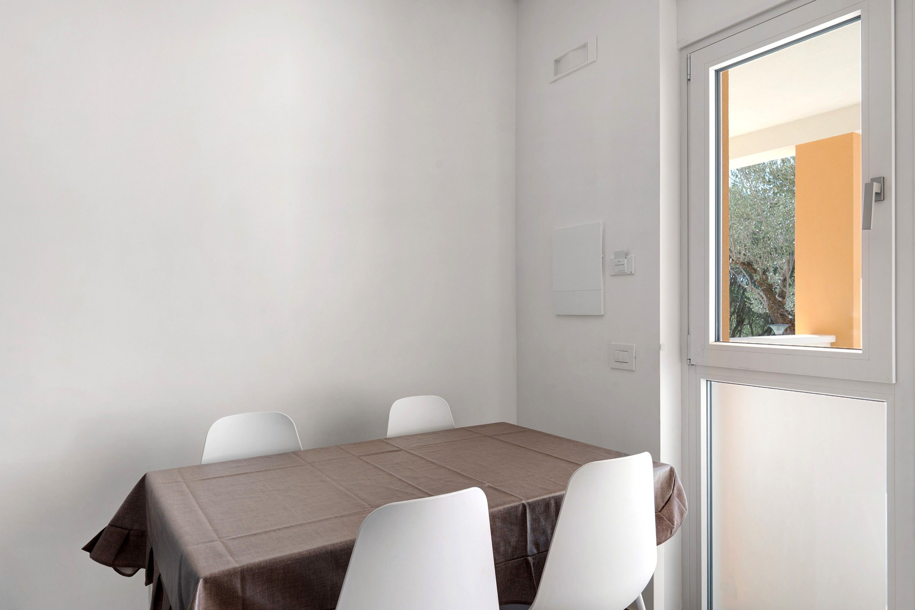 Une pièce avec une table et quatre chaises, une fenêtre et une porte.