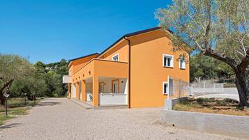 A two-story building with a covered outdoor area and a gravel driveway.