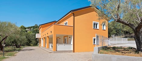 A two-story building with a covered outdoor area and a gravel driveway.