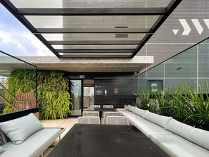 A modern outdoor seating area with a glass ceiling, a green wall with plants, and a lounge sign. - At Self by Hosppedar (João Pessoa)