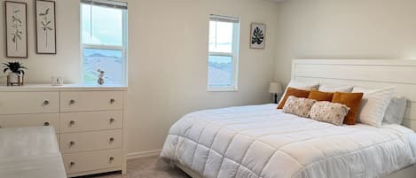 Une chambre à coucher avec un lit, une commode et deux fenêtres.