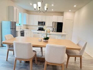 A modern kitchen with white cabinetry, a wooden dining table, and four chairs. - Winter Haven 5BR Family Retreat- Near LEGOLAND + Disney, Family-Friendly (Winter Haven)