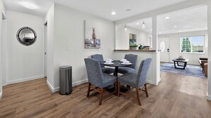 A modern dining area with a round table and patterned chairs, a trash can, and a mirror on the wall. - 2 Bed Cottage, Close to Tacoma Mall, Freeways (Tacoma)