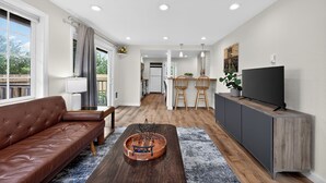 A modern living room with a leather sofa, a wooden coffee table, and a TV on a cabinet. - 2 Bed Cottage, Close to Tacoma Mall, Freeways (Tacoma)