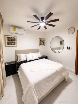 A bedroom with a bed, a ceiling fan, a wall clock, and framed artwork. - Family Luxury Villa  Primaveral 4 / Near Beaches (La Altagracia)
