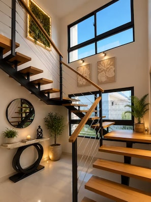 A modern staircase with wooden steps and black railings, leading to a second floor with large windows and a view of the outside. - Family Luxury Villa  Primaveral 4 / Near Beaches (La Altagracia)