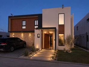 A modern two-story house with a car parked in the driveway. - Family Luxury Villa  Primaveral 4 / Near Beaches (La Altagracia)
