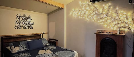 A bedroom with a bed, a wall-mounted air conditioner, and a decorative wall piece.