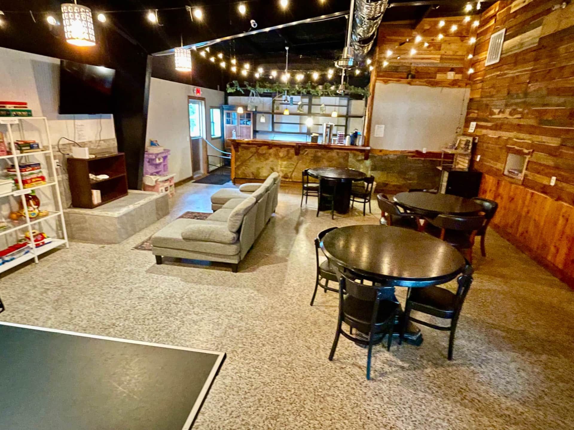 Un espace intérieur accueillant, avec un canapé, deux tables rondes et une bibliothèque.