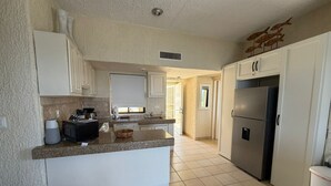 A kitchen with white cabinets, a granite countertop, a stainless steel refrigerator, and a window with a view. - Peaceful 2BR/2BA condo with Wrap-Around patio that overlooks the Sea of Cortez. (Cabo San Lucas)