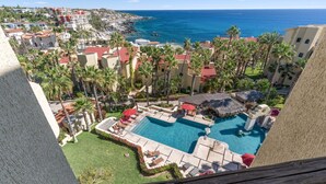 A resort with a swimming pool, palm trees, and a view of the ocean. - Peaceful 2BR/2BA condo with Wrap-Around patio that overlooks the Sea of Cortez. (Cabo San Lucas)