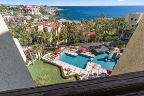 A resort with a swimming pool, palm trees, and a view of the ocean. - Peaceful 2BR/2BA condo with Wrap-Around patio that overlooks the Sea of Cortez. (Cabo San Lucas)