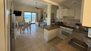 A kitchen with a view of the ocean, a dining area with a table and chairs, and a living area with a sofa. - Peaceful 2BR/2BA condo with Wrap-Around patio that overlooks the Sea of Cortez. (Cabo San Lucas)