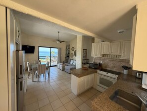 A kitchen with a view of the ocean, a dining area with a table and chairs, and a living area with a sofa. - Peaceful 2BR/2BA condo with Wrap-Around patio that overlooks the Sea of Cortez. (Cabo San Lucas)