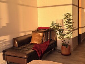 A modern living room with a leather sofa, a red throw blanket, and a potted plant. - Luxury Experience | Panoramic View (Sunset) (Bogotá)