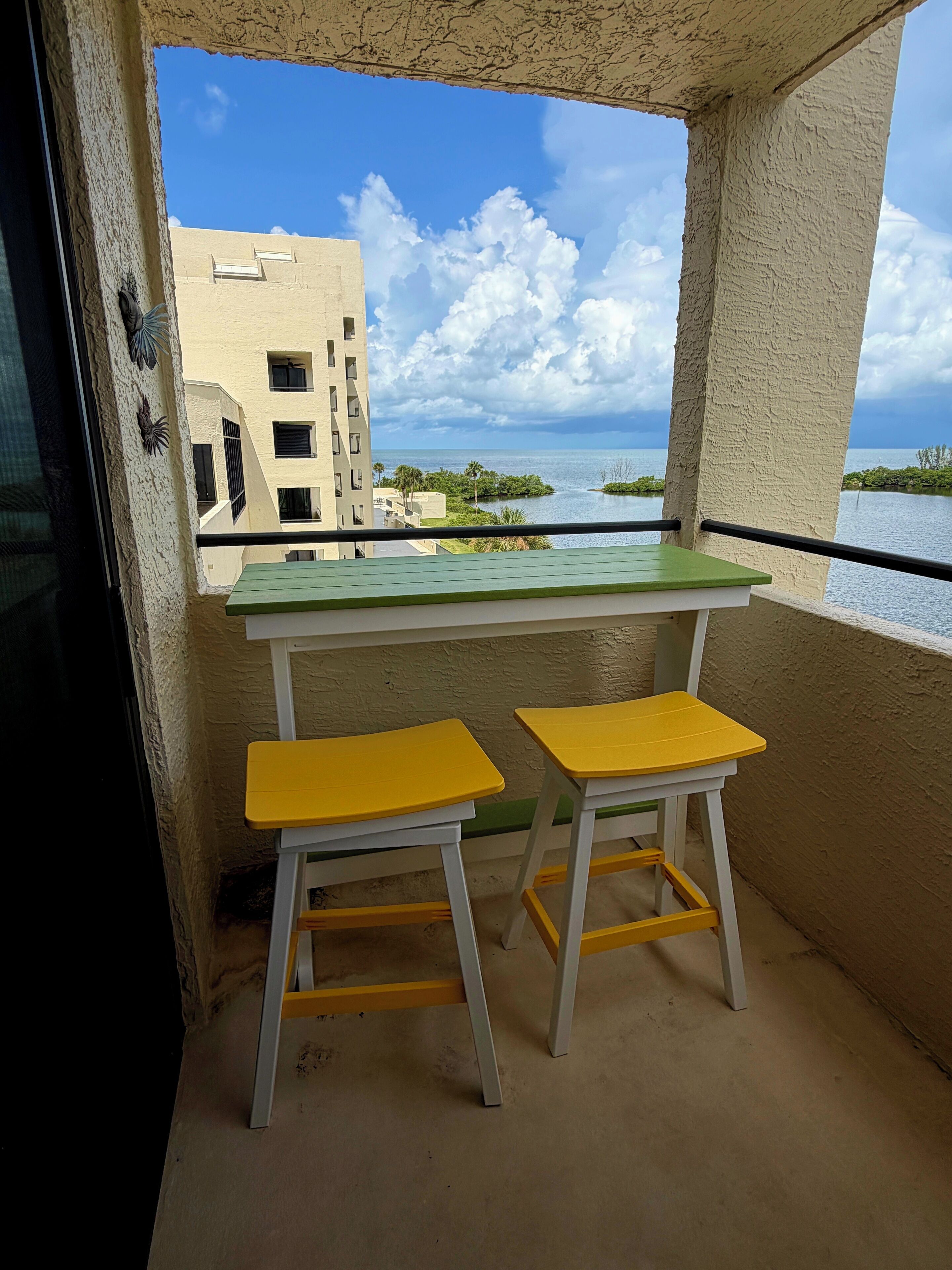 Ein Balkon mit Blick auf ein Gewässer, ein Gebäude und einen klaren Himmel.