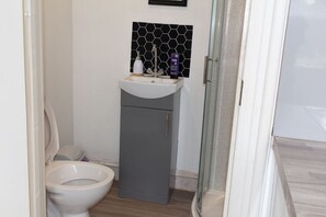 A bathroom with a toilet, a sink, and a glass shower enclosure.