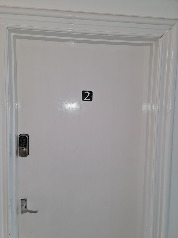A white door with a number 2 sign, a keypad lock, and a door handle.