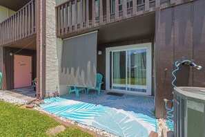 Een overdekt buitengebied met een schuifpui, een patio stoel en een kleine tafel.