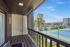 A balcony with a view of a tennis court and high-rise buildings. - Sapphire Shores, Steps to the Beach, Sleeps 8 (Panama City Beach)