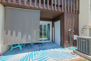 Ein Balkon mit ausrollbarem Sichtschutz, einer Tür zu einer Glastür sowie einer Klimaanlage.