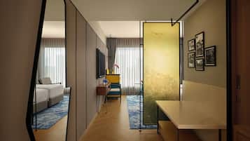 Une chambre d’hôtel avec un grand miroir, un canapé, une petite table sur laquelle est posé un vase de fleurs, et une carte accrochée au mur.