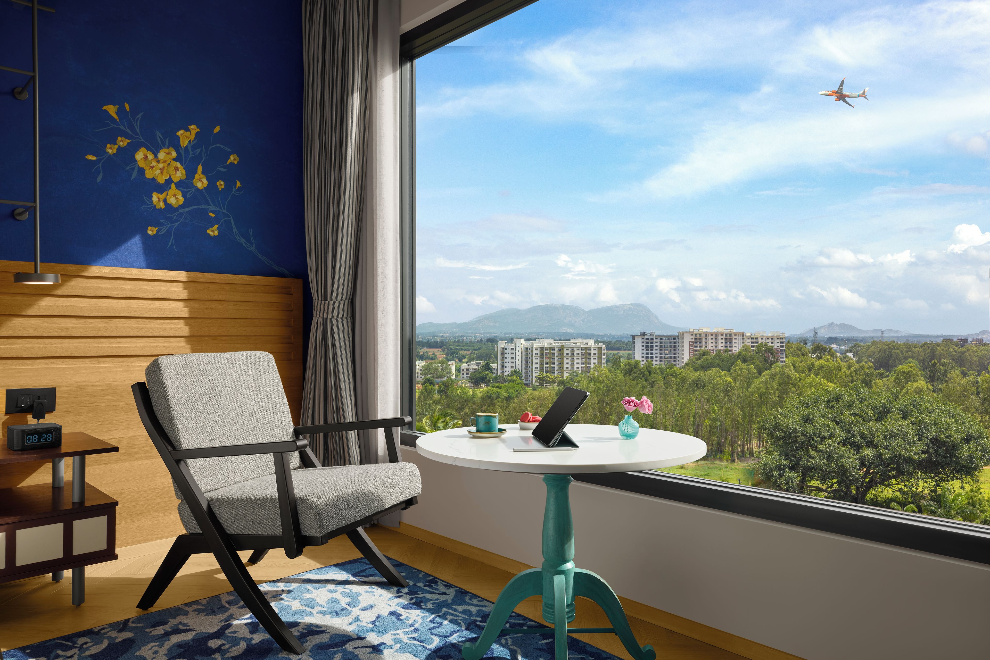 Habitación de hotel moderna con vistas a un paisaje urbano y montañas.