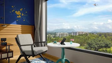 Habitación de hotel moderna con vistas a un paisaje urbano y montañas.