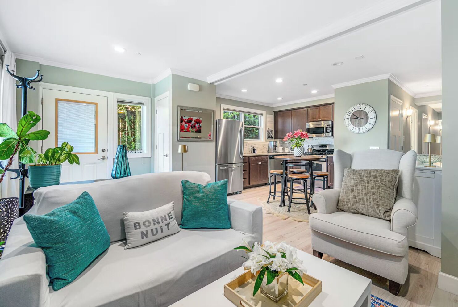 A modern living room with a sofa, a coffee table, and a dining area with a kitchen in the background.