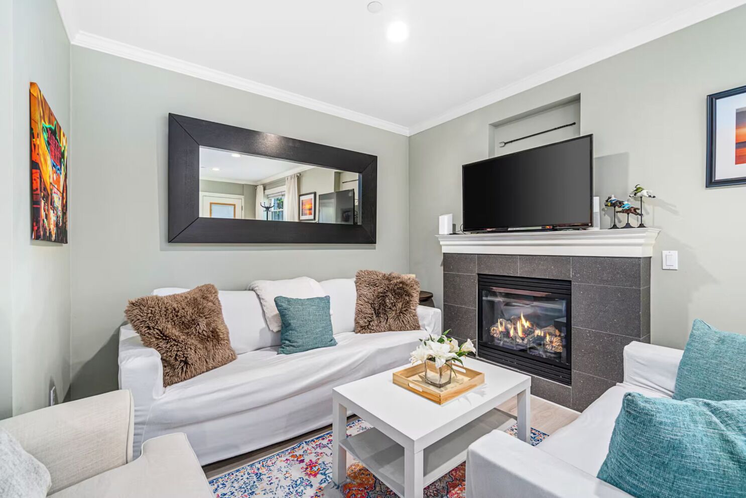 A modern living room with a fireplace, a sofa, a coffee table, and a flat-screen TV.