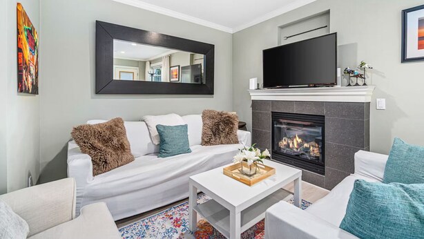 A modern living room with a fireplace, a sofa, a coffee table, and a flat-screen TV. - Stunning 2-bed Apt in the Heart of Queen Anne (Seattle)