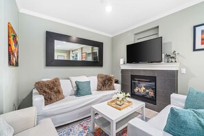 A modern living room with a fireplace, a sofa, a coffee table, and a flat-screen TV. - Stunning 2-bed Apt in the Heart of Queen Anne (Seattle)