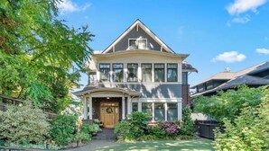 A two-story house with a front porch, a brick facade, and a well-maintained garden. - Stunning 2-bed Apt in the Heart of Queen Anne (Seattle)