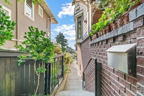 A narrow residential street with brick walls, a metal gate, and a wooden fence. - Stunning 2-bed Apt in the Heart of Queen Anne (Seattle)