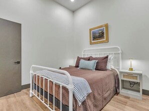 Ein Schlafzimmer mit einem Bett, einem Nachttisch und einem gerahmten Bild an der Wand.