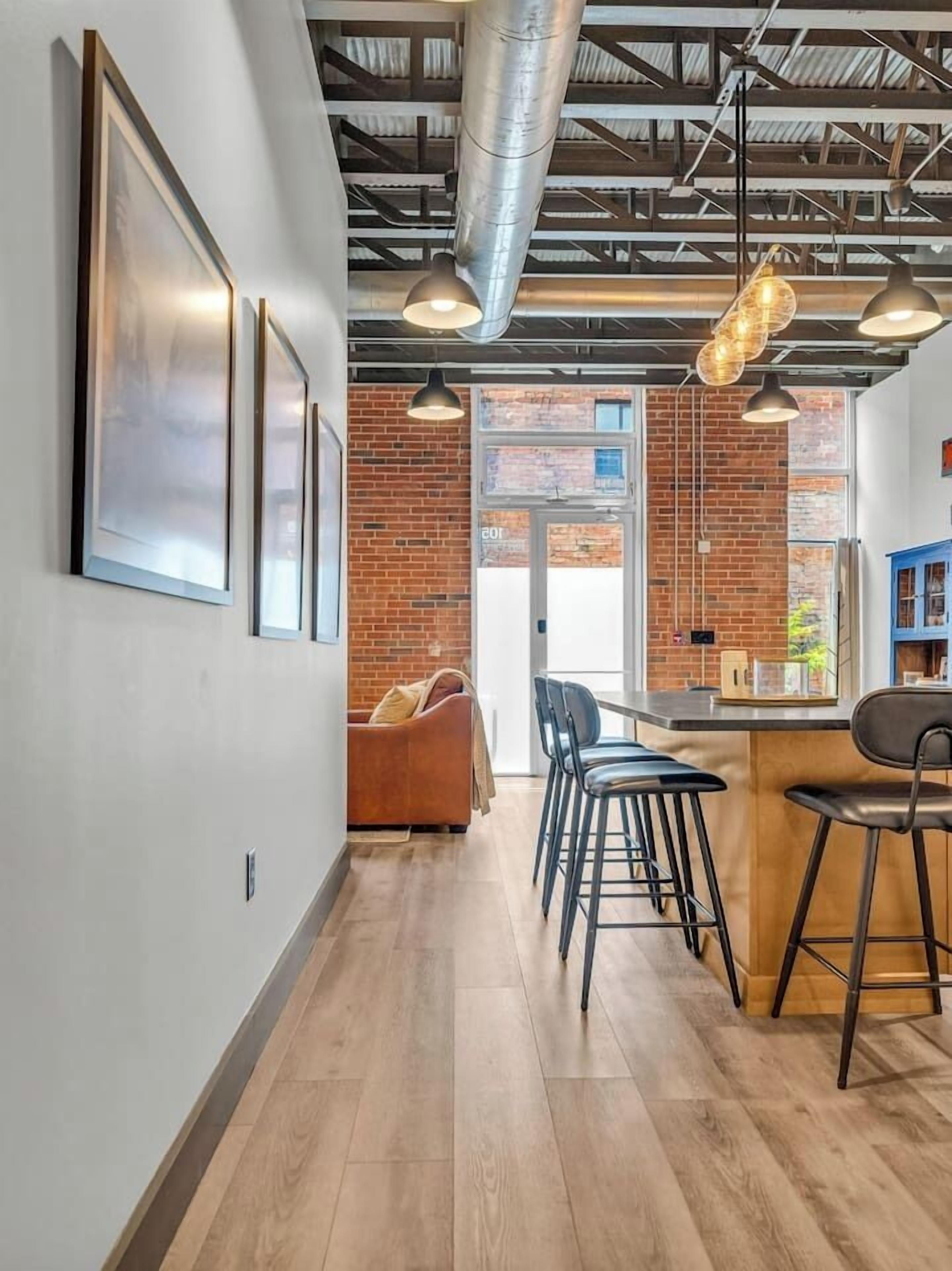 A modern interior with a bar area, seating, and exposed brick walls.