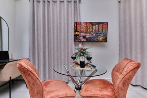 Ein modernes Wohnzimmer mit einem Glastisch, zwei orangefarbenen Sesseln, einem Gemälde an der Wand und einem Kamin.