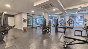Una palestra con diverse attrezzature, ampie finestre e una pianta.