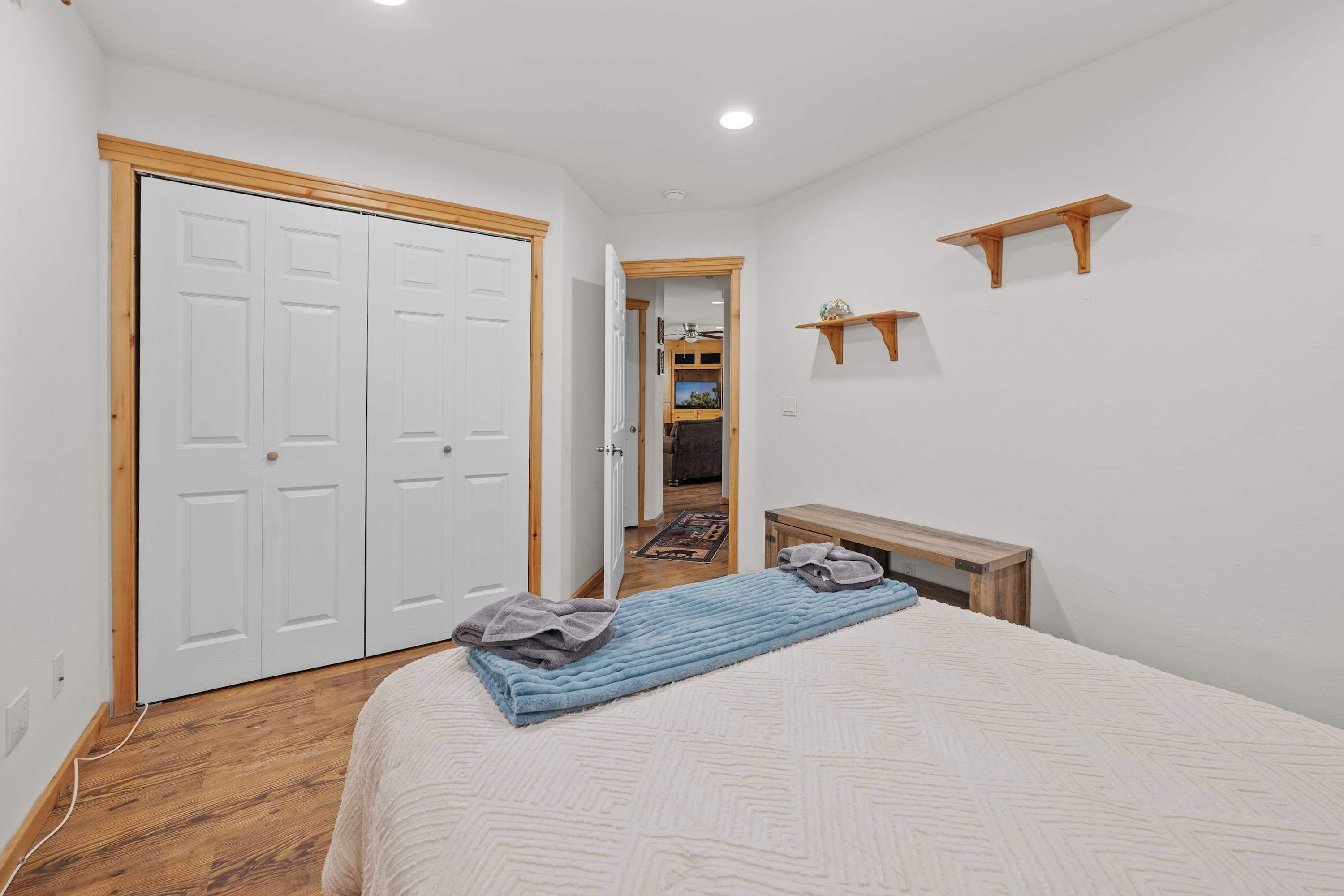 A bedroom with a bed, a wooden bench, a small table, and a door.